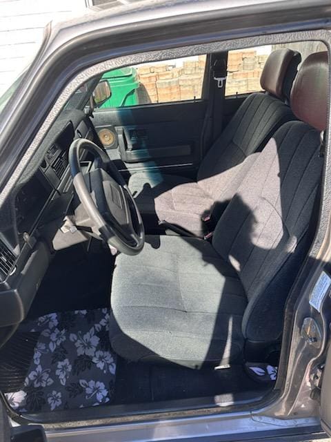 Interior view of a car showing the driver's seat and steering wheel.