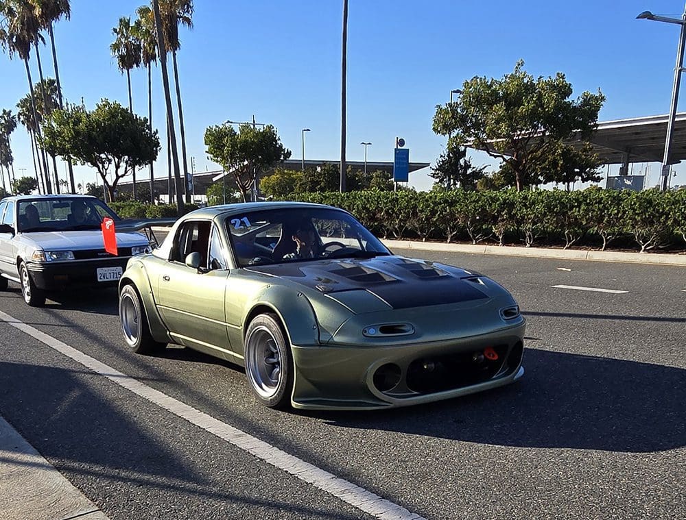 A sleek green sports car parked by the roadside on a sunny day.