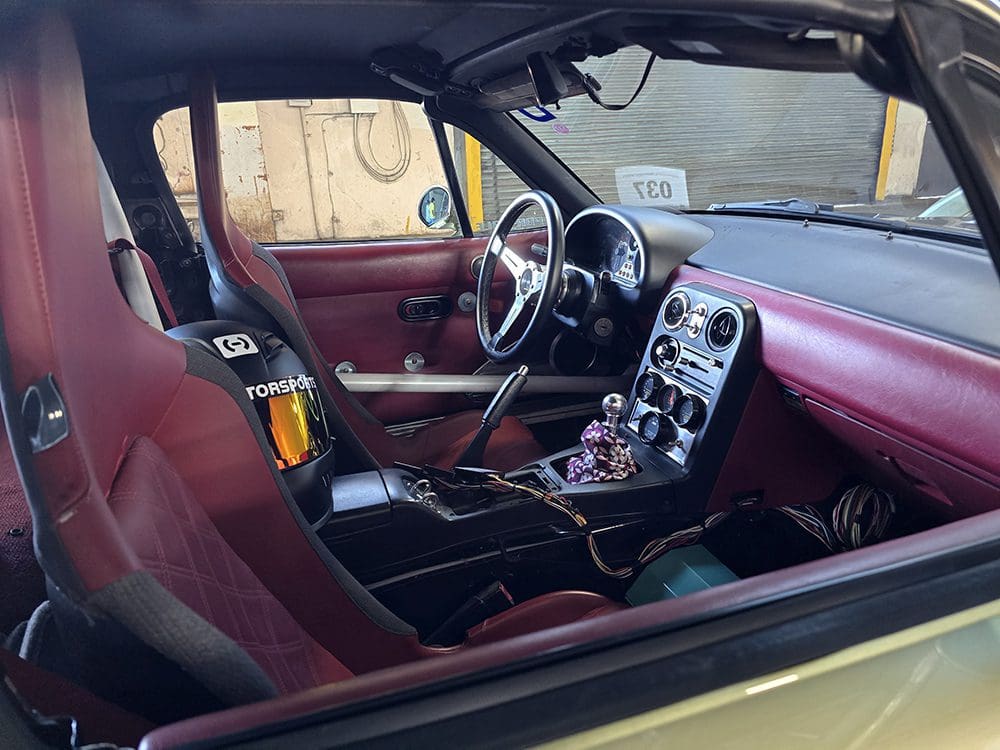 Interior of a classic car with burgundy seats and dashboard.