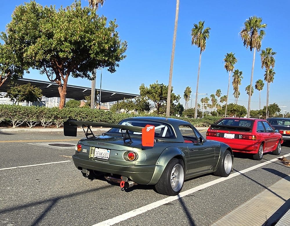Classic green convertible sports car parked with a cooler on the trunk.