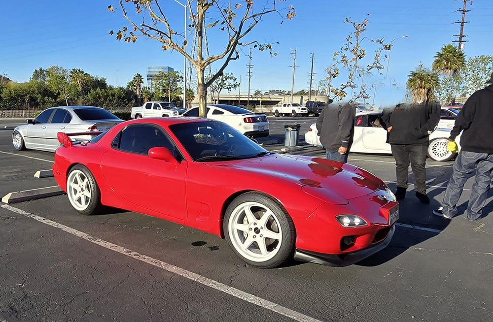A red sports car parked in an outdoor lot on a sunny day.