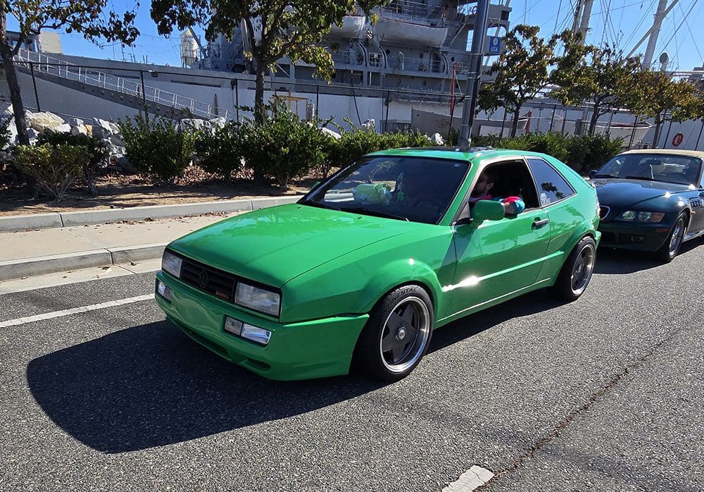 Green customized car parked on a street with urban background.