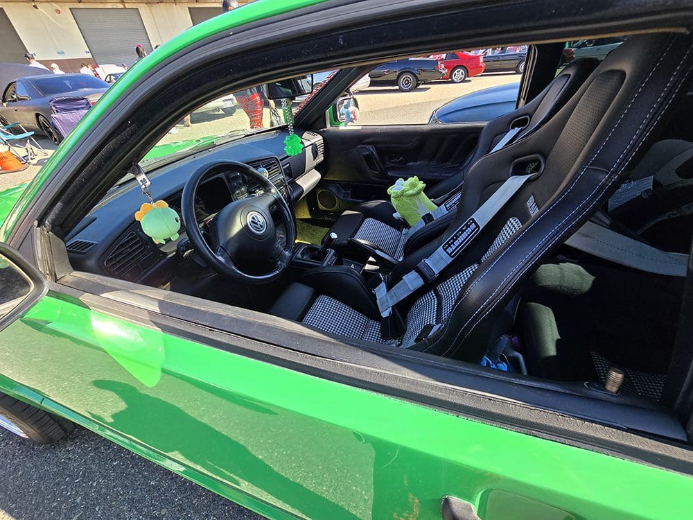 Interior of a green sports car showcasing its steering wheel and seats.
