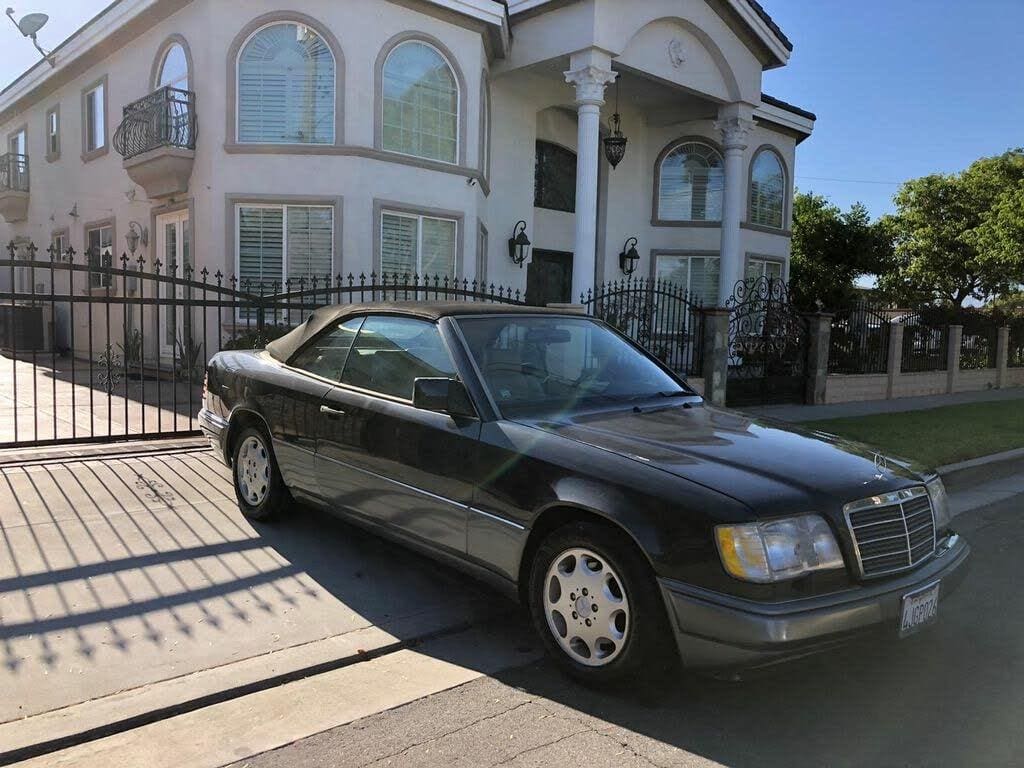 A black luxury sedan parked outside a residential house on a sunny day.