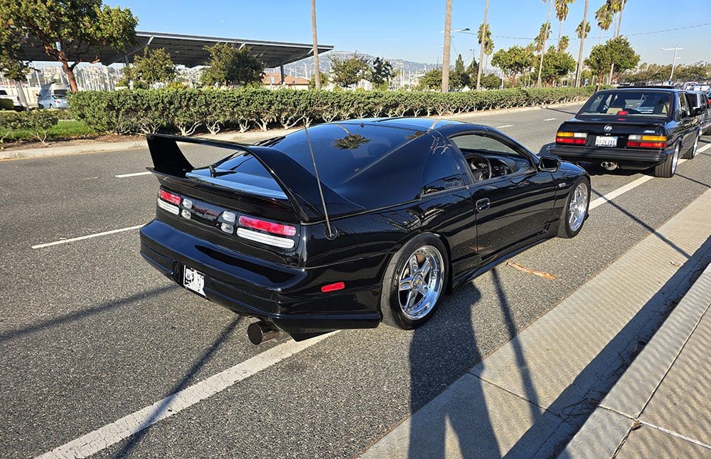 Black sports car parked by the roadside on a sunny day.