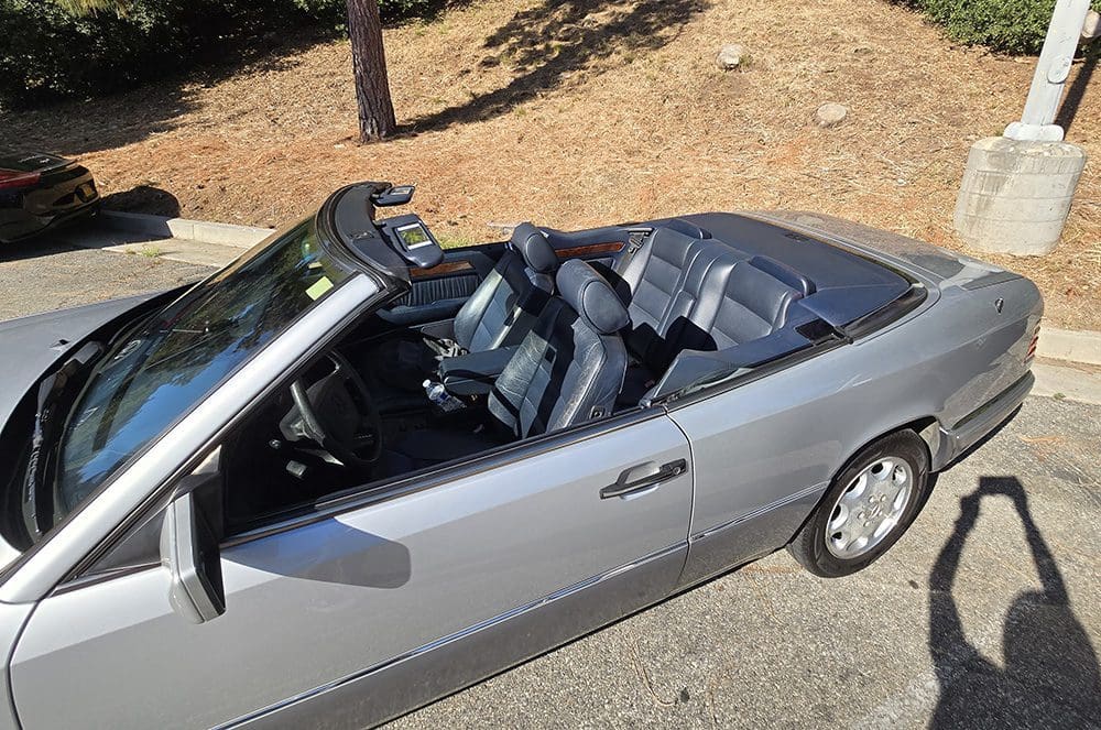 Silver convertible car parked outdoors on a sunny day.