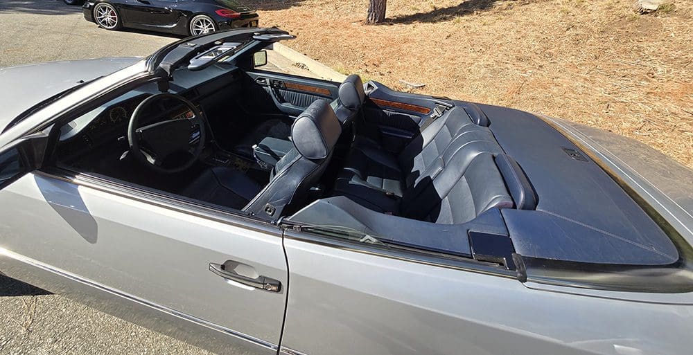 Interior of a convertible car with black leather seats and dashboard.