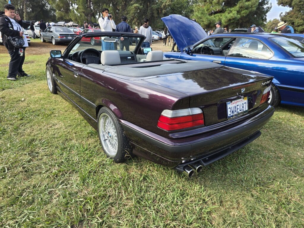 A vintage maroon convertible car at an outdoor car show.