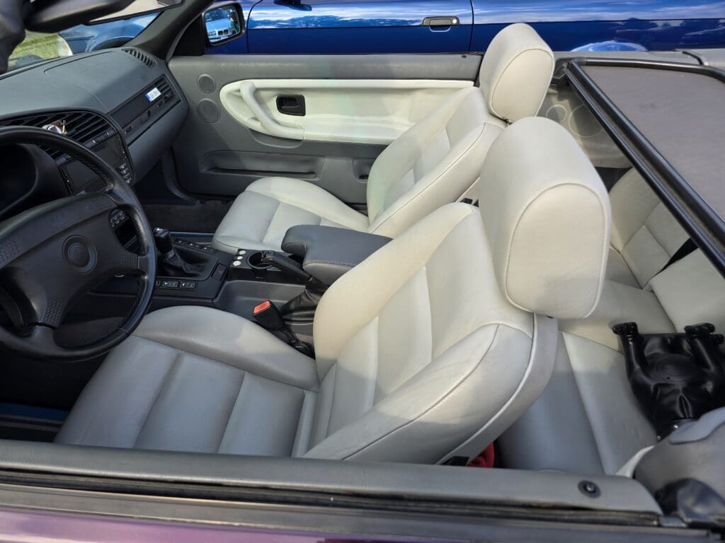 Interior view of a classic convertible car with beige leather seats.