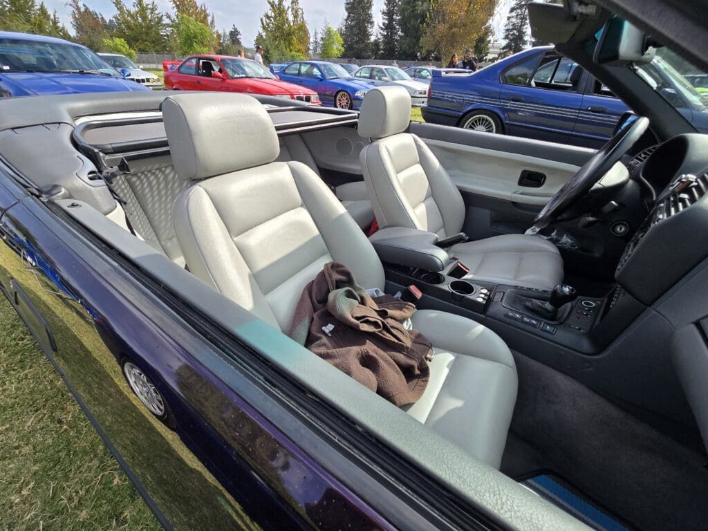 Convertible car with light gray leather seats and folded soft top.