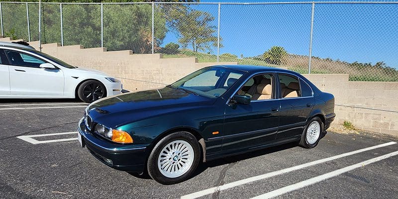 Dark green BMW sedan parked in a sunny outdoor lot.