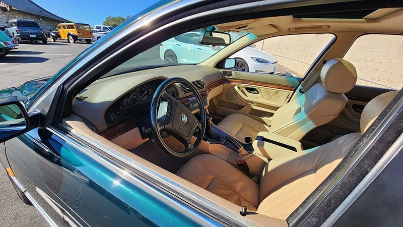 Interior view of a car showing the steering wheel and beige seats.