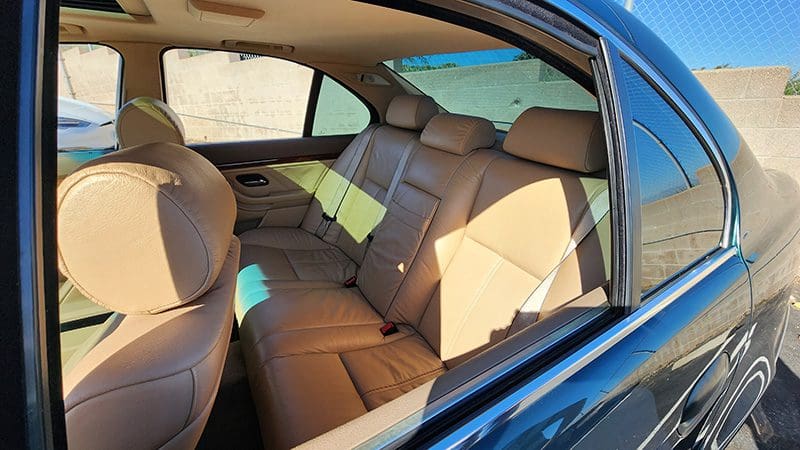 Interior view of a car showing tan leather back seats and door panel.