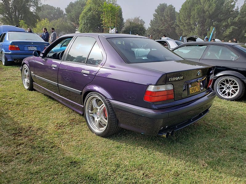 Purple BMW sedan parked on grass beside another car.
