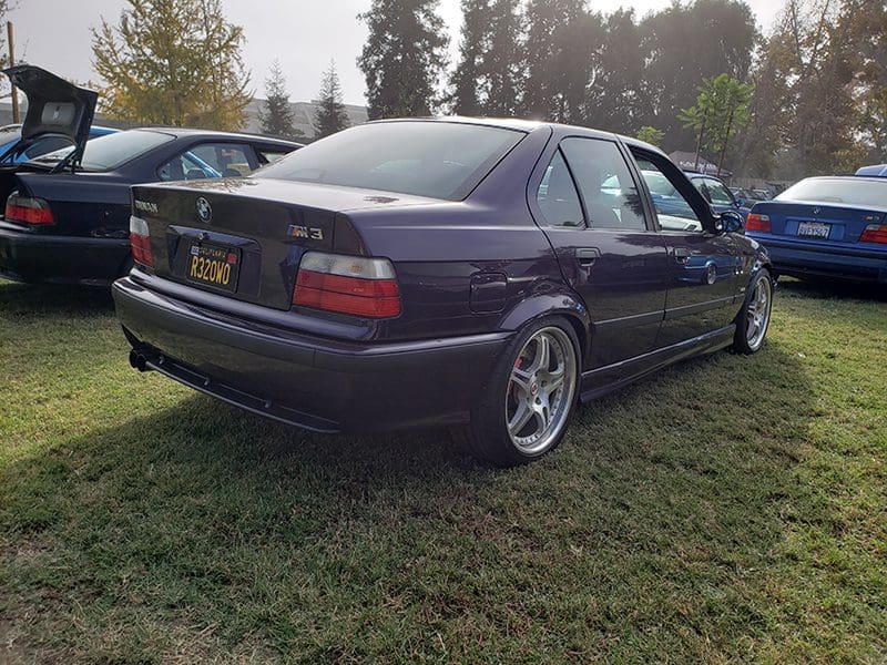 Classic dark blue BMW parked on grass at an outdoor event.