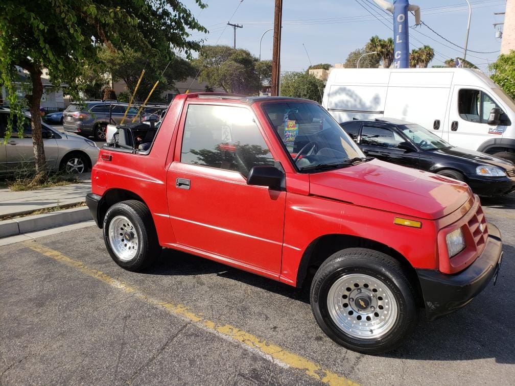 Red compact convertible SUV parked outdoors on a sunny day.