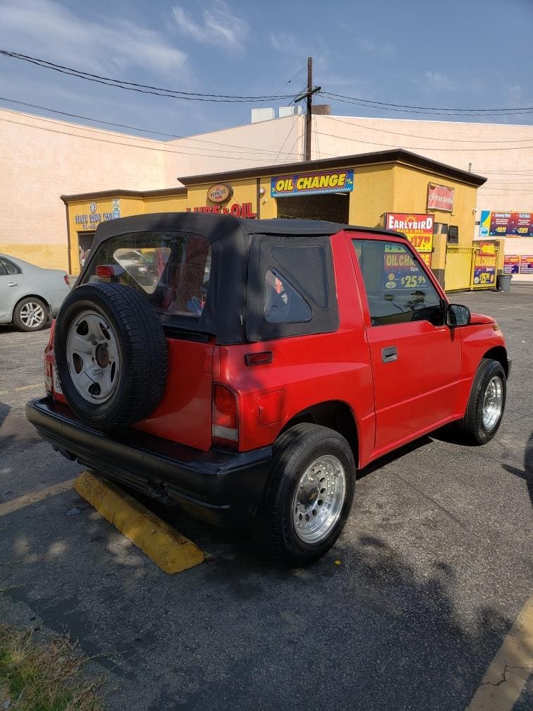 Red compact SUV parked outside a yellow building.