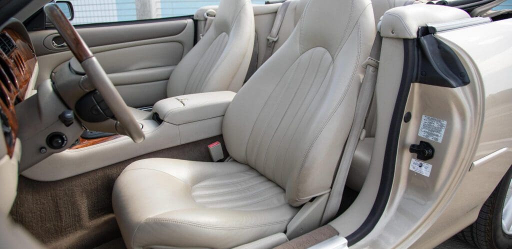 Close-up of a beige leather car seat with detailed stitching.