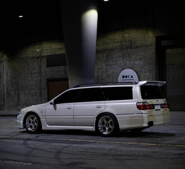 White station wagon parked on a dimly lit street at night.