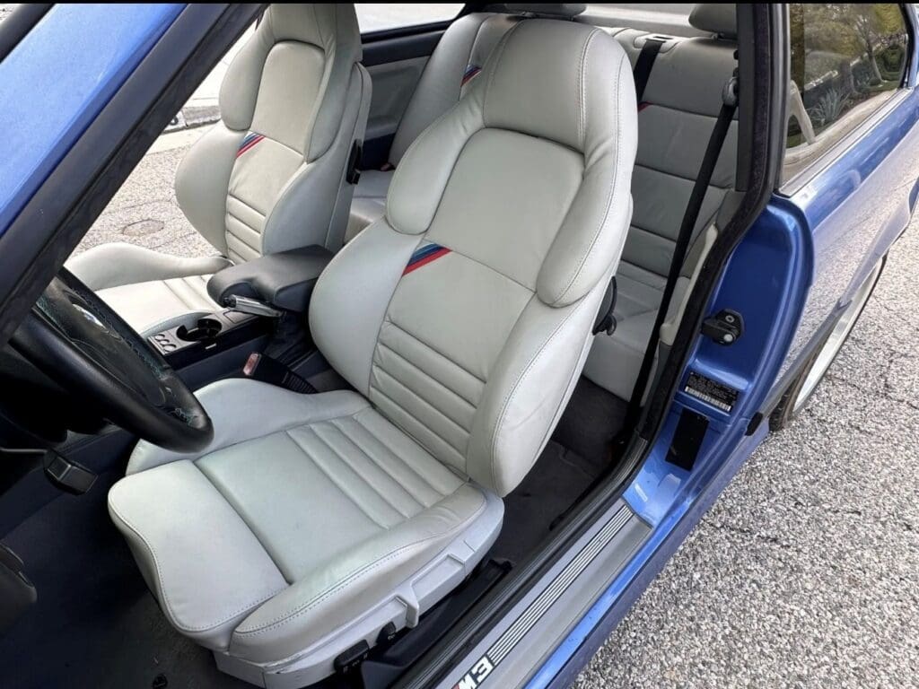 Luxurious white leather car seats in a blue vehicle.
