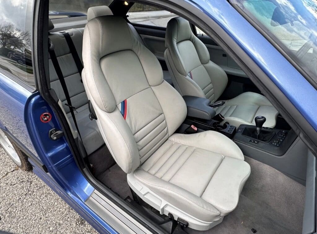 Close-up of beige leather car seats inside a blue vehicle.