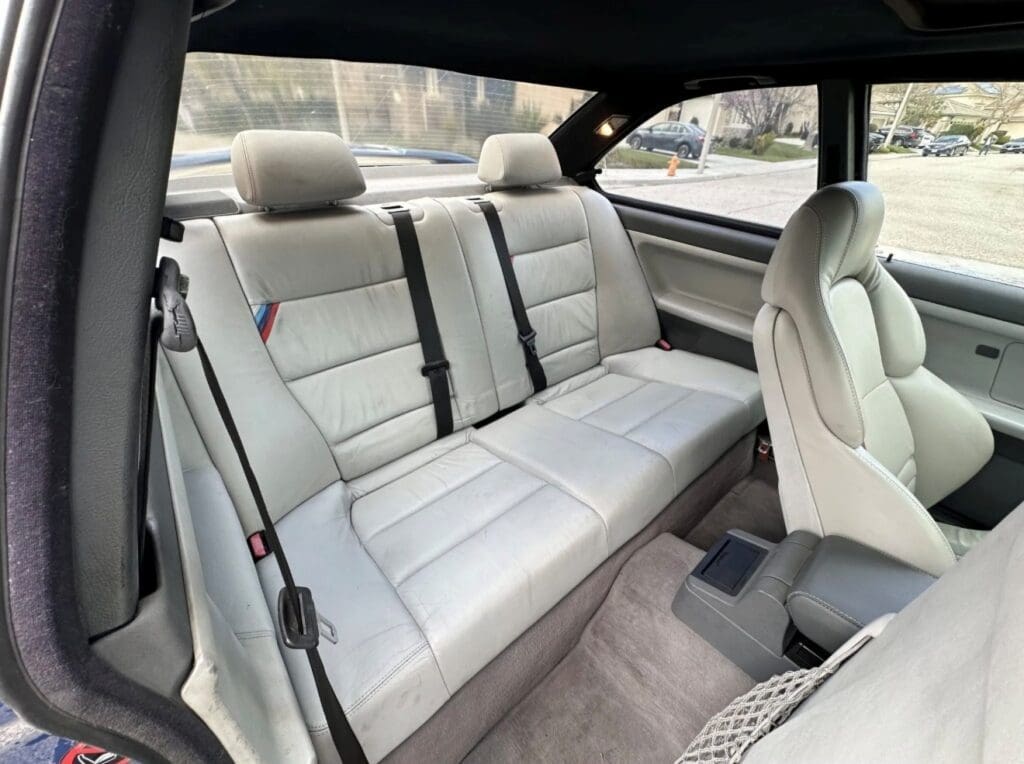 Clean light gray leather rear car seats with seat belts.
