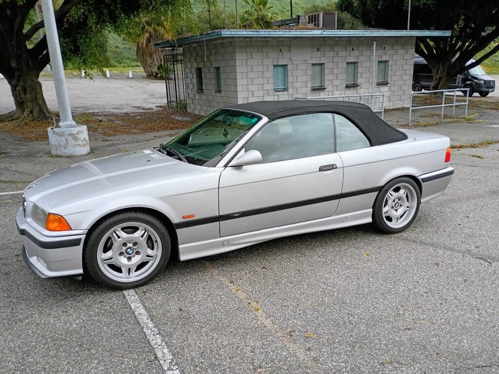 Silver convertible sports car parked near a building.