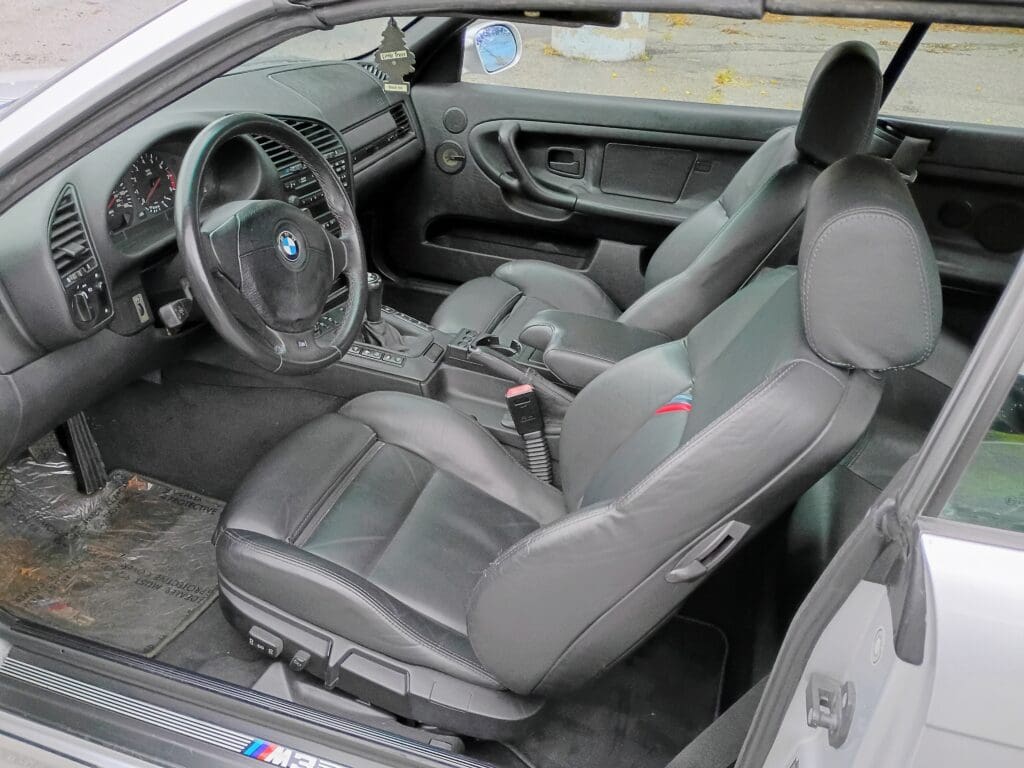 Interior of a modern car featuring black leather seats and a detailed dashboard.