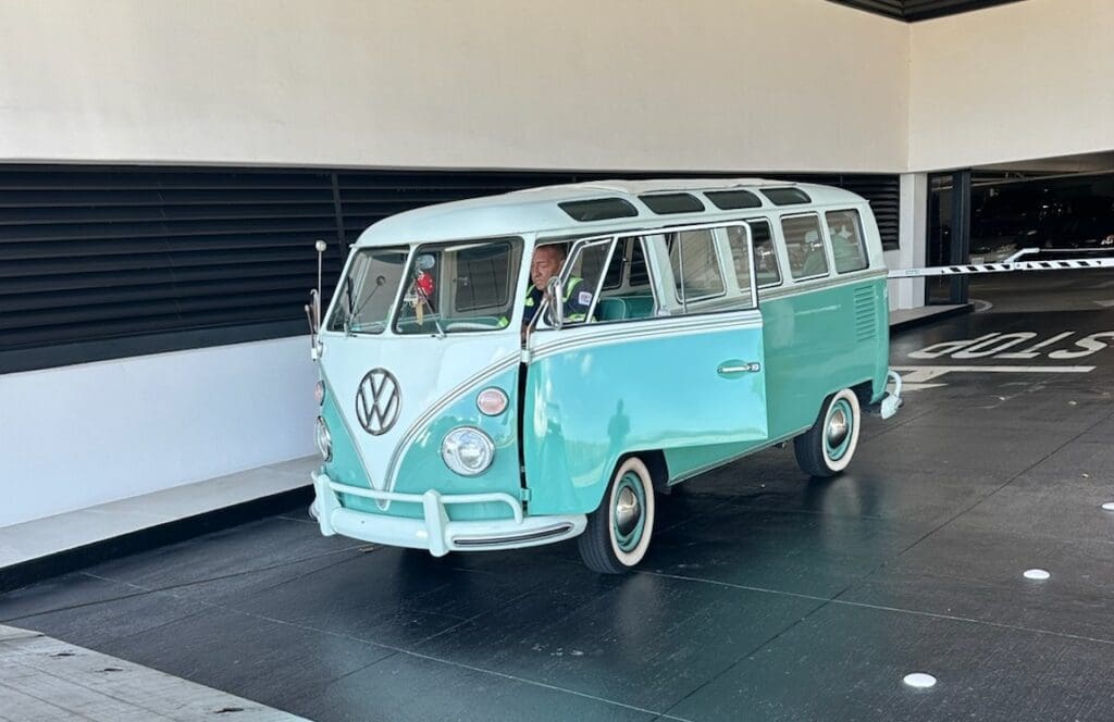 Vintage teal Volkswagen van parked outside building.