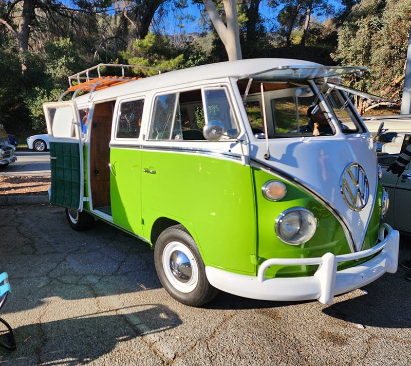 Green vintage van parked outdoors, door open.