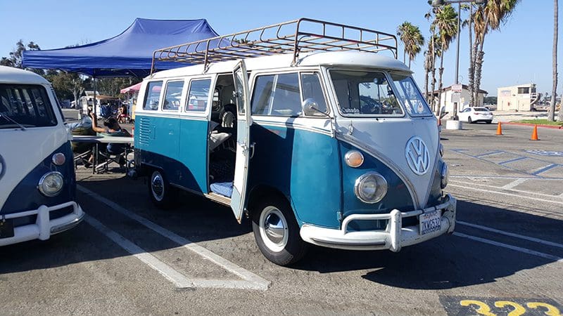Vintage blue Volkswagen van in parking lot.