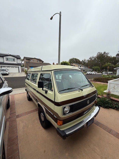 Vintage van parked in suburban neighborhood driveway.