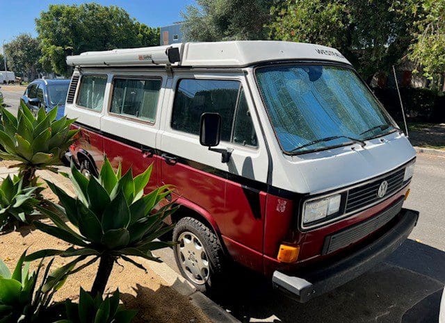 Red and white camper van parked roadside.